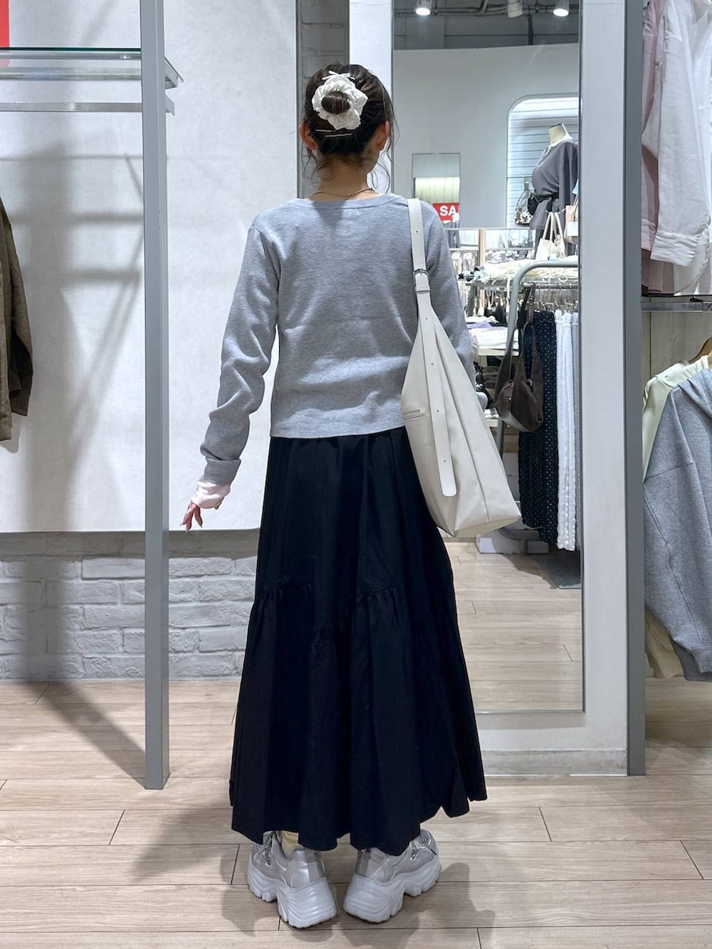 ホワイト系のショルダーバッグ、ピンク系のTシャツ/カットソー、ブラック系のスカートを着用したレディースの春コーディネートの5枚目の写真