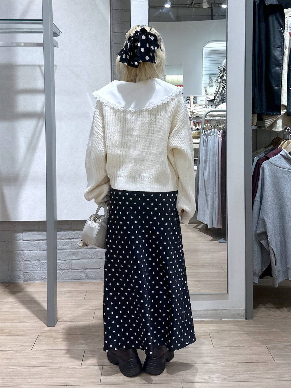 ブラック系のスカート、ホワイト系のボストンバッグ、ブラウン系のローファーを着用したレディースの冬コーディネートの5枚目の写真