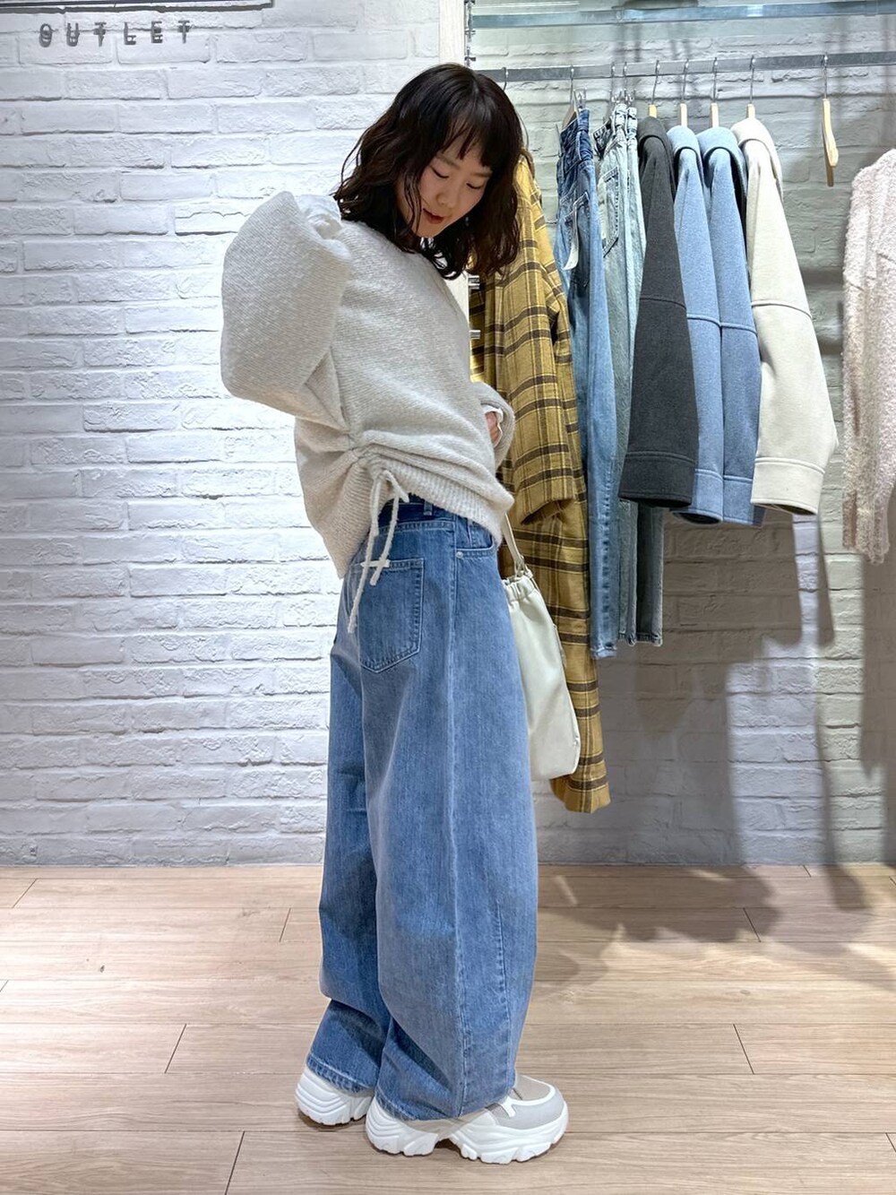 ブルー系のデニムパンツ、ホワイト系のショルダーバッグ、ベージュ系のスニーカーを着用したレディースの冬コーディネートの2枚目の写真