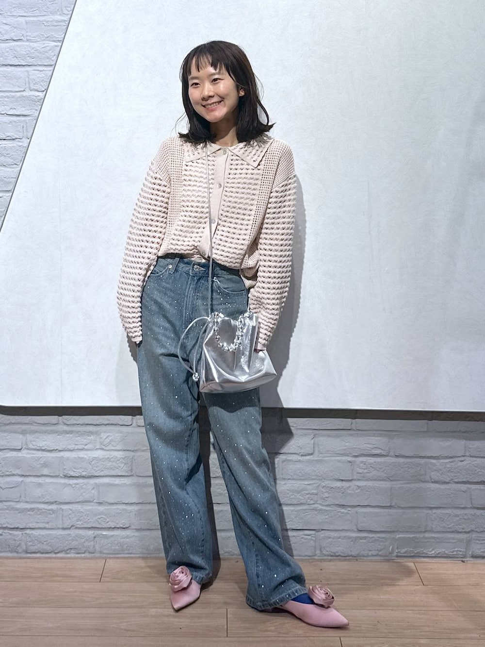 ピンク系のパンプス、シルバー系のショルダーバッグ、ブルー系のデニムパンツを着用したレディースの秋コーディネートの5枚目の写真