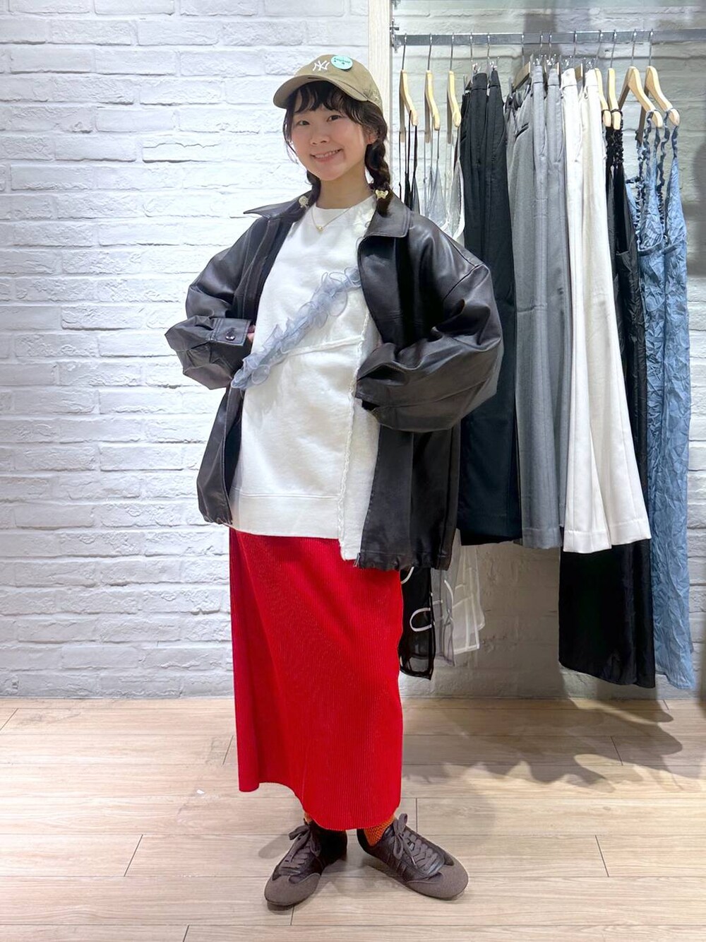 レッド系のスカート、ブラウン系のブルゾン、ホワイト系のスウェットを着用したレディースの春コーディネートの2枚目の写真