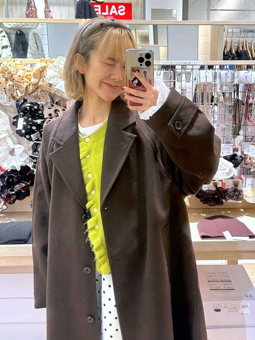 ホワイト系のスカート、ブラウン系のチェスターコート、ホワイト系のTシャツ/カットソーを着用したレディースの秋コーディネートの3枚目の写真