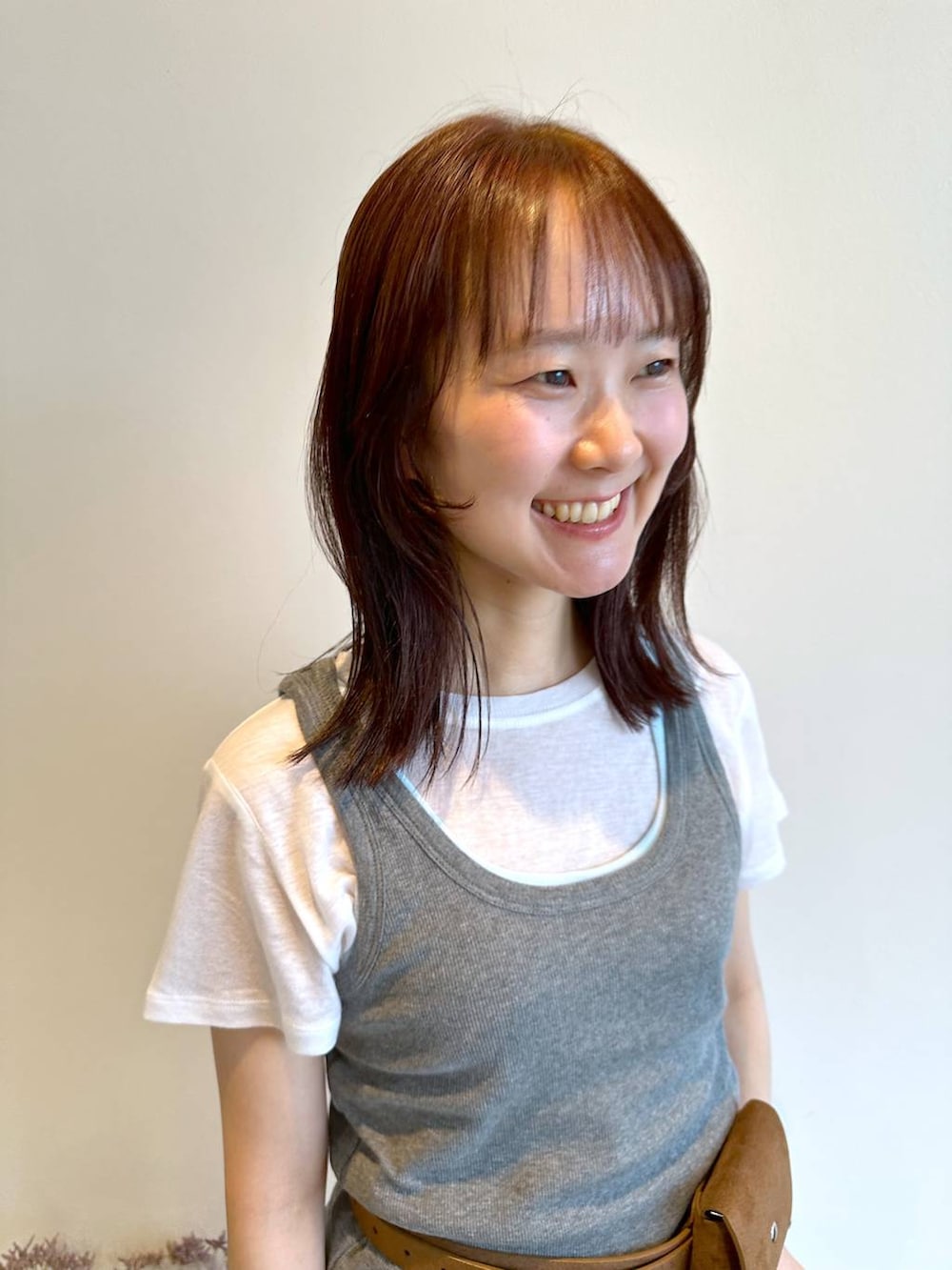 グレー系のタンクトップ、ホワイト系のTシャツ/カットソー、イエロー系のベルトを着用したレディースの夏コーディネートの2枚目の写真