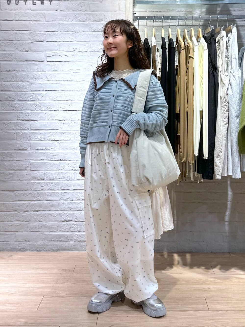 ベージュ系のショルダーバッグ、ホワイト系のTシャツ/カットソー、ブルー系のニット/セーターを着用したレディースの春コーディネートの5枚目の写真