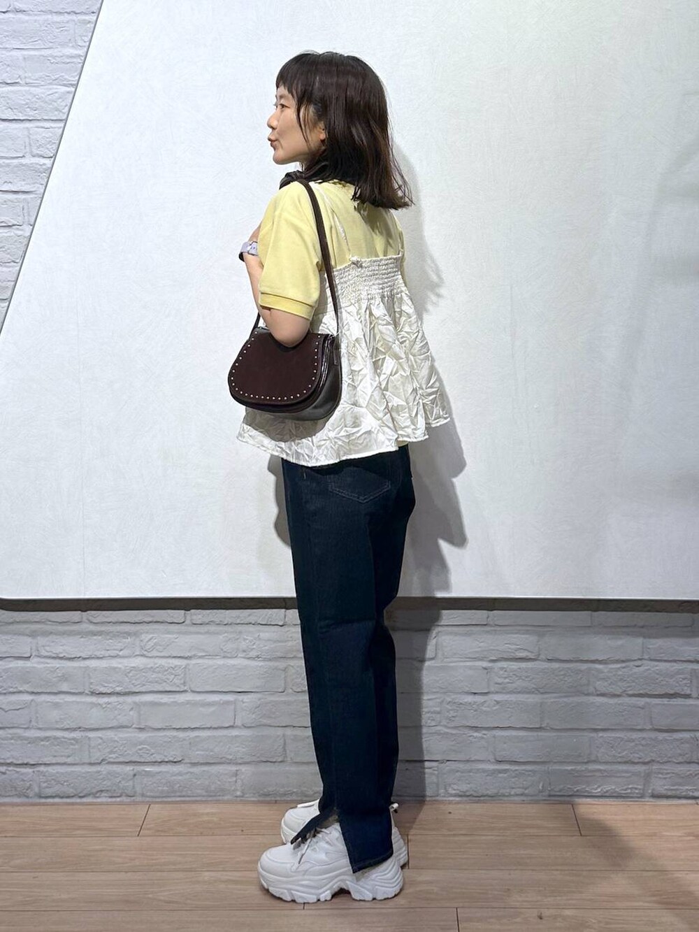 イエロー系のTシャツ/カットソー、ブラウン系のショルダーバッグ、ブルー系のデニムパンツを着用したレディースの秋コーディネートの3枚目の写真