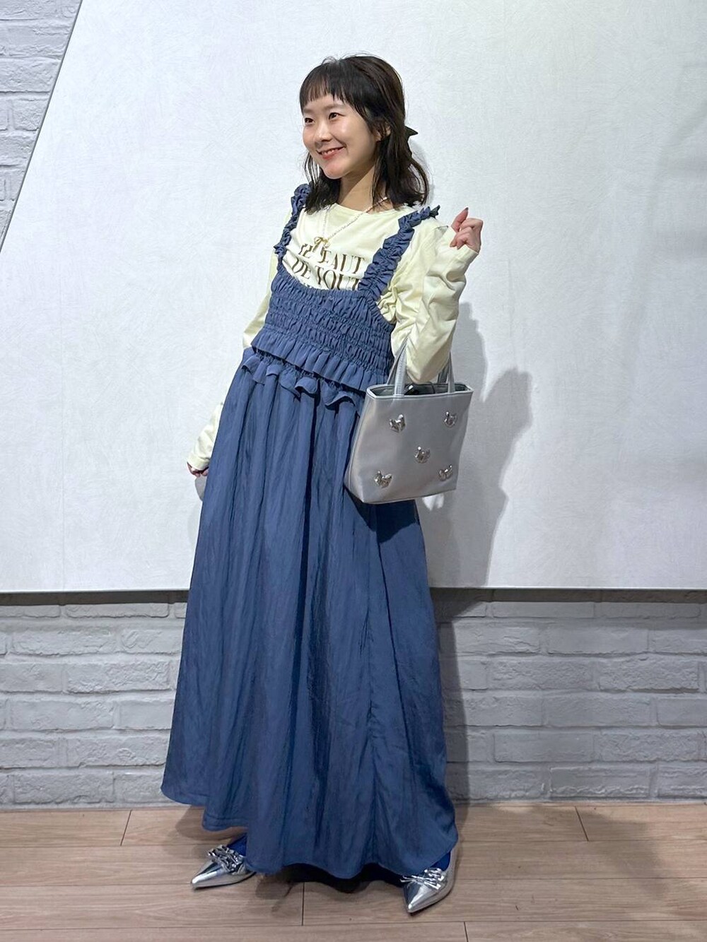 シルバー系のショルダーバッグ、シルバー系のパンプス、イエロー系のTシャツ/カットソーを着用したレディースの夏コーディネートの2枚目の写真