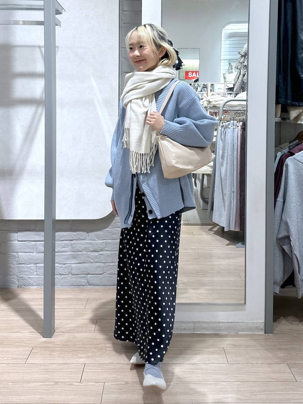 ブラック系のスカート、ブルー系のカーディガン/ボレロ、ホワイト系のパンプスを着用したレディースの冬コーディネートの2枚目の写真