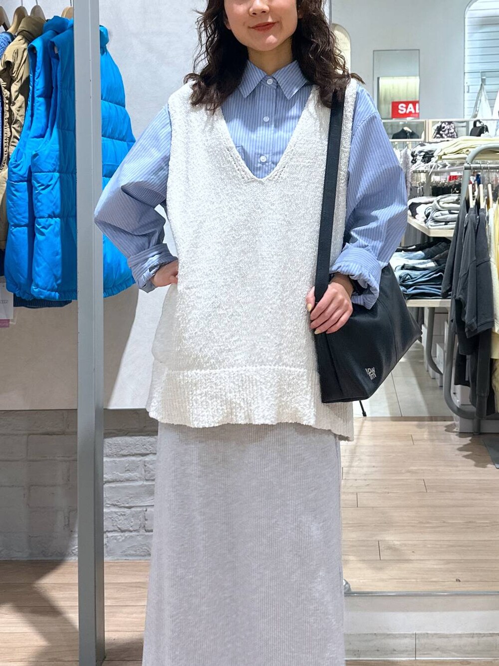 グレー系のスカート、ブルー系のシャツ/ブラウス、ホワイト系のニット/セーターを着用したレディースの春コーディネートの3枚目の写真