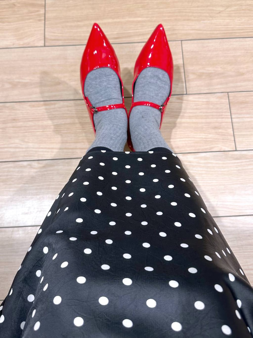 ブラック系のスカート、レッド系のパンプス、グレー系のニット/セーターを着用したレディースの冬コーディネートの2枚目の写真