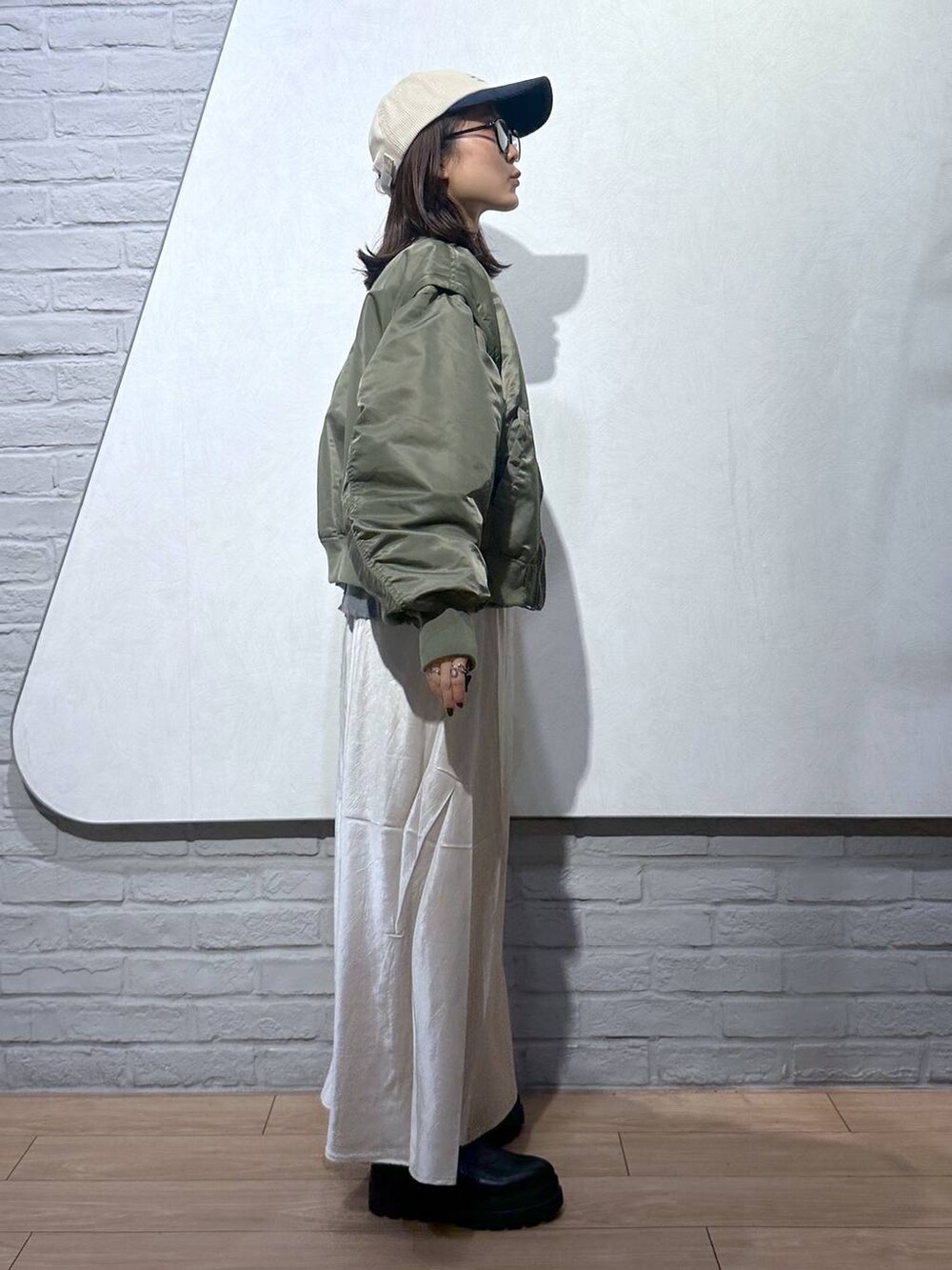 ブラック系のブーツ、ホワイト系のスカート、グレー系のスウェットを着用したレディースの秋コーディネートの2枚目の写真