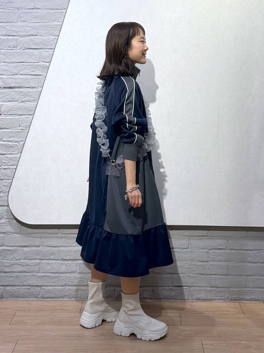 ホワイト系のブーツ、ブルー系のワンピース、グレー系のスマホグッズを着用したレディースの秋コーディネートの3枚目の写真