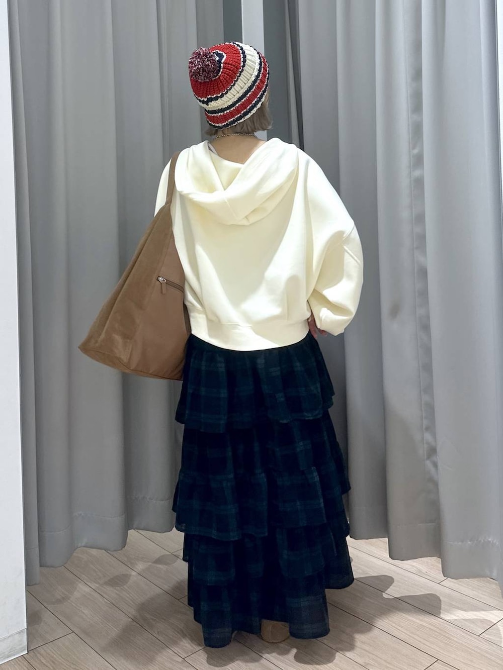 ベージュ系のショルダーバッグ、ブラウン系のスニーカー、グリーン系のスカートを着用したレディースの秋コーディネートの5枚目の写真