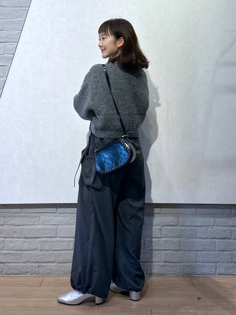 グレー系のワンピース、ブラック系のショルダーバッグ、ホワイト系のTシャツ/カットソーを着用したレディースの秋コーディネートの4枚目の写真