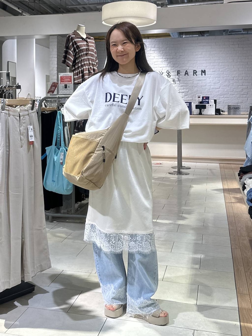 ベージュ系のショルダーバッグ、ホワイト系のTシャツ/カットソー、ブルー系のデニムパンツを着用したレディースの夏コーディネートの5枚目の写真