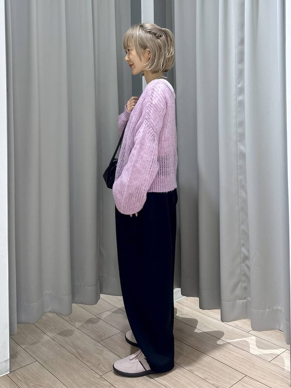 ピンク系のスニーカー、ブラック系のスウェットパンツ、ブラック系のショルダーバッグを着用したレディースの秋コーディネートの2枚目の写真