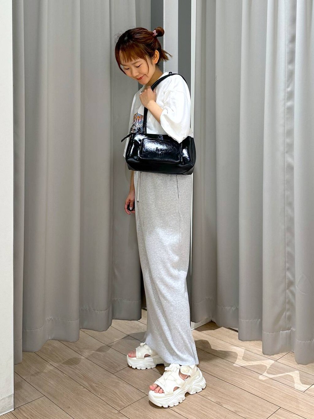 グレー系のスカート、ホワイト系のサンダル、ホワイト系のTシャツ/カットソーを着用したレディースの夏コーディネートの2枚目の写真