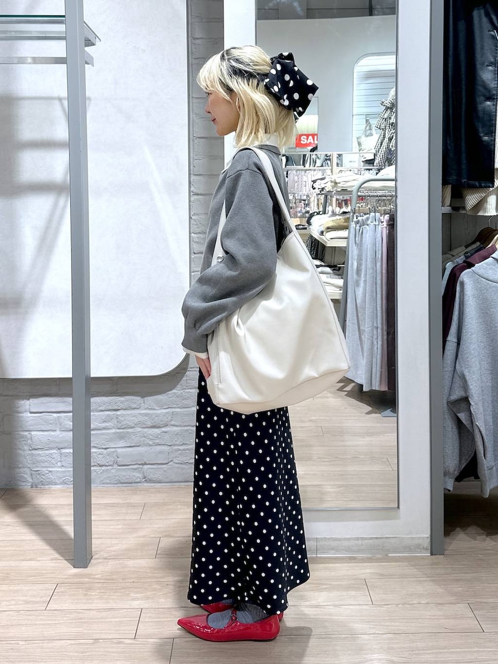 ブラック系のスカート、レッド系のパンプス、ホワイト系のショルダーバッグを着用したレディースの冬コーディネートの3枚目の写真