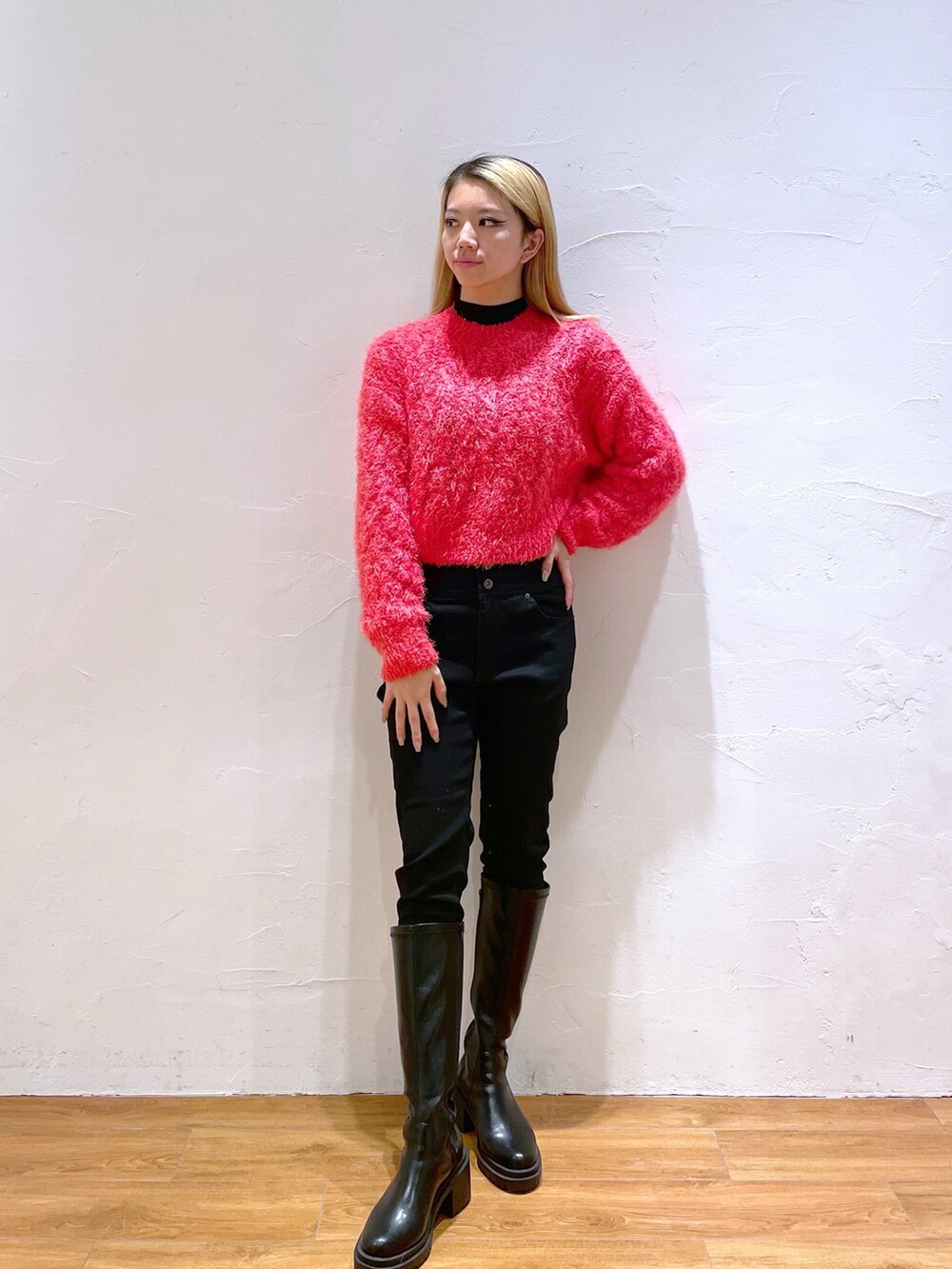 ブラック系のデニムパンツ、ブラック系のブーツ、レッド系のニット/セーターを着用したレディースの秋コーディネートの2枚目の写真