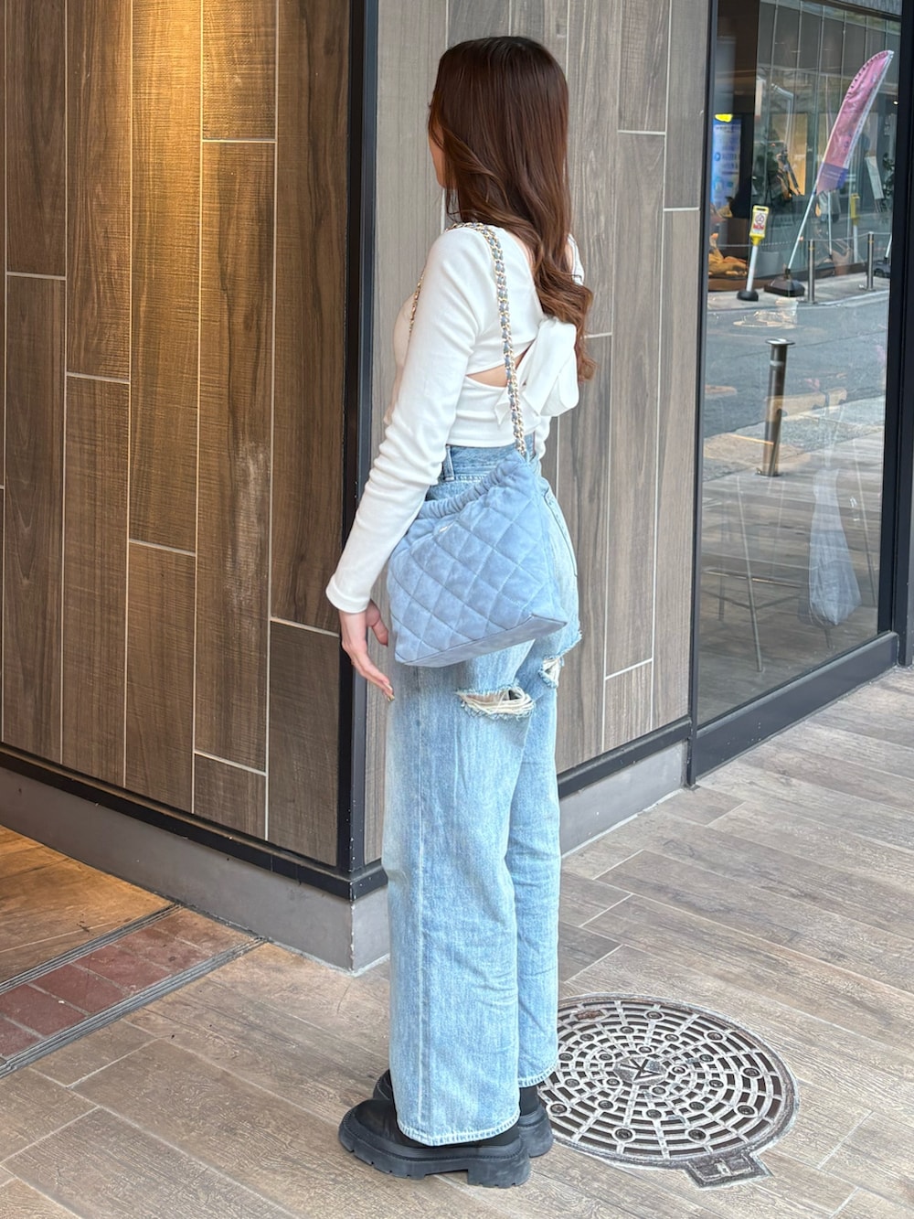 ホワイト系のTシャツ/カットソー、ブルー系のデニムパンツ、ブラック系のブーツを着用したレディースの春コーディネートの2枚目の写真