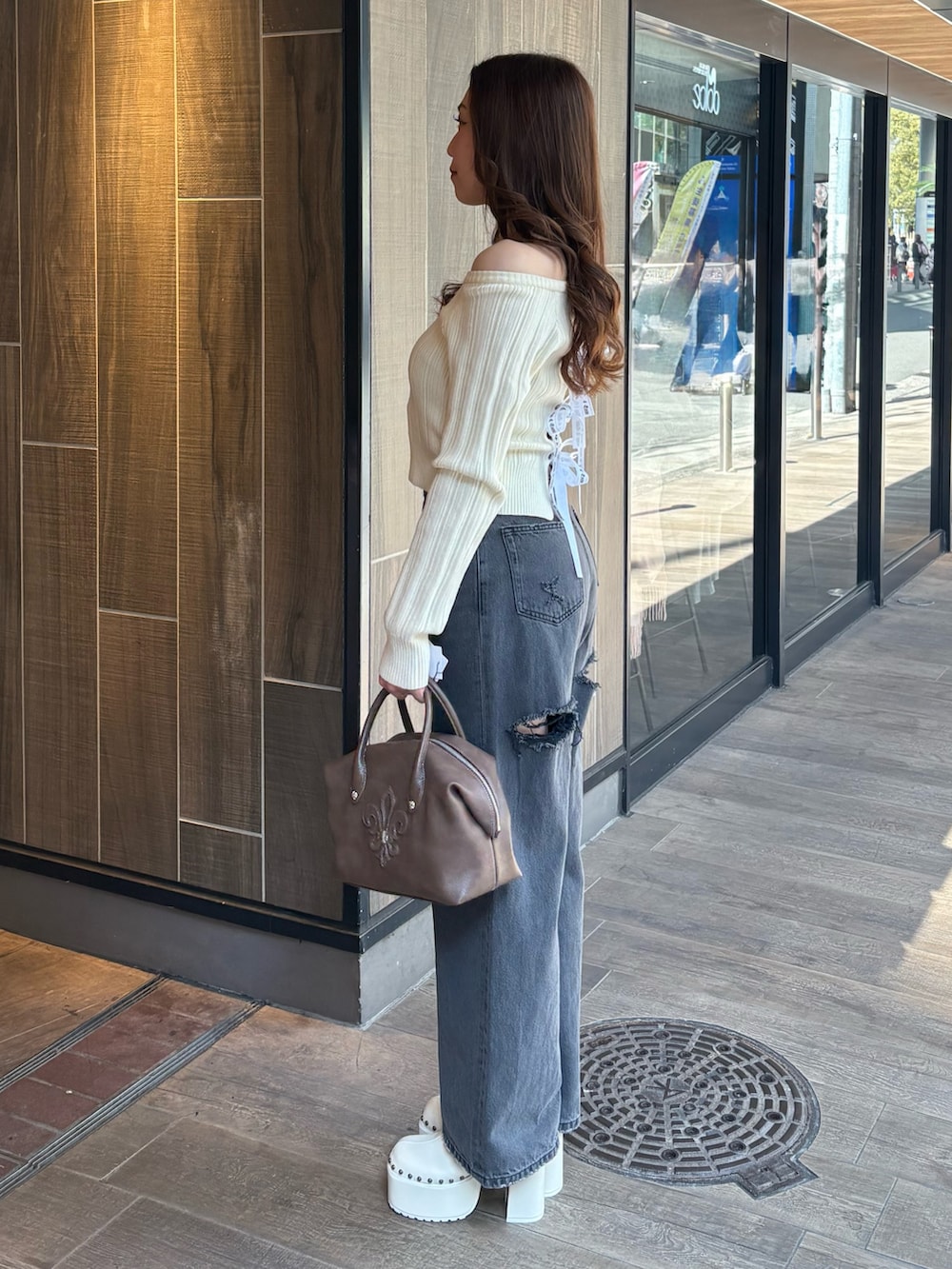 ホワイト系のニット/セーター、ブラック系のデニムパンツ、ブラウン系のボストンバッグを着用したレディースの冬コーディネートの2枚目の写真