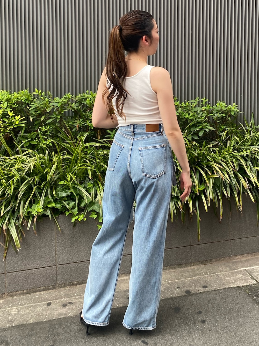 ホワイト系のタンクトップ、ブルー系のデニムパンツ、ブラック系のサンダルを着用したレディースの夏コーディネートの2枚目の写真