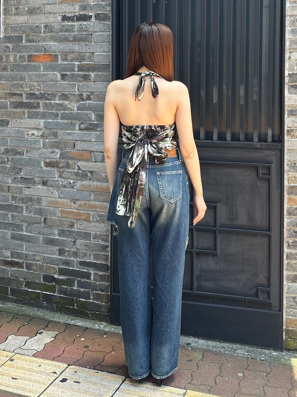 ブルー系のデニムパンツ、グリーン系のキャミソール、ブラック系のサンダルを着用したレディースの夏コーディネートの3枚目の写真