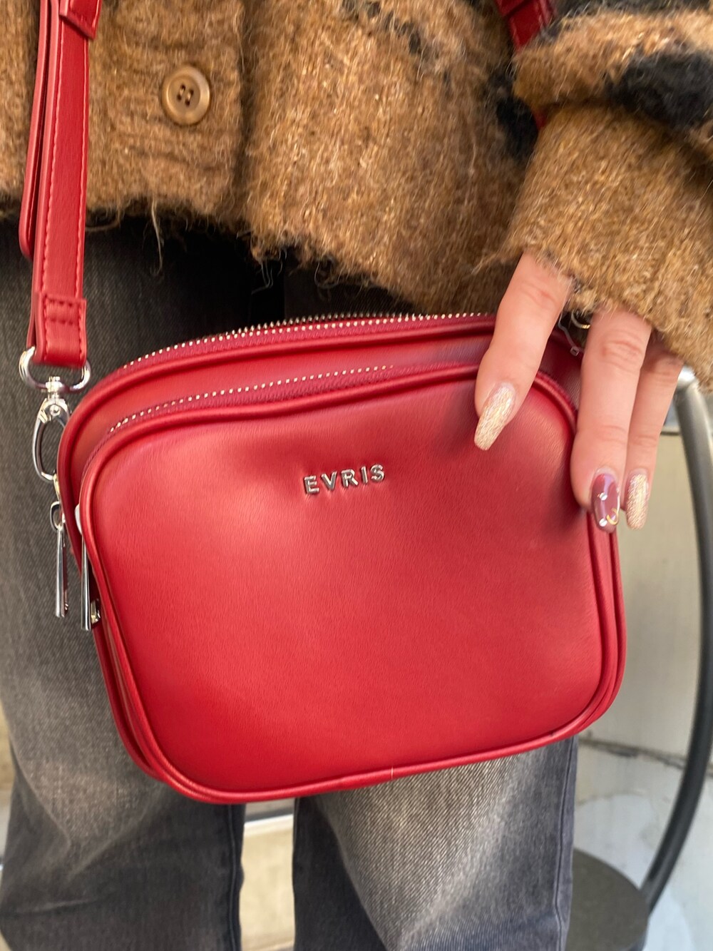 ブラック系のデニムパンツ、ブラウン系のニット/セーター、レッド系のショルダーバッグを着用したレディースの秋コーディネートの8枚目の写真