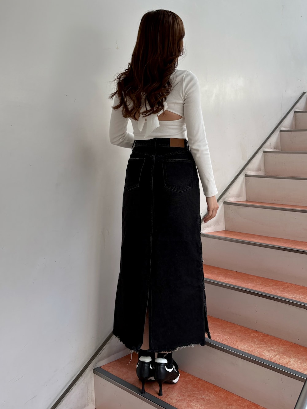 ホワイト系のTシャツ/カットソー、ブラック系のデニムスカート、ブラック系のパンプスを着用したレディースの春コーディネートの3枚目の写真