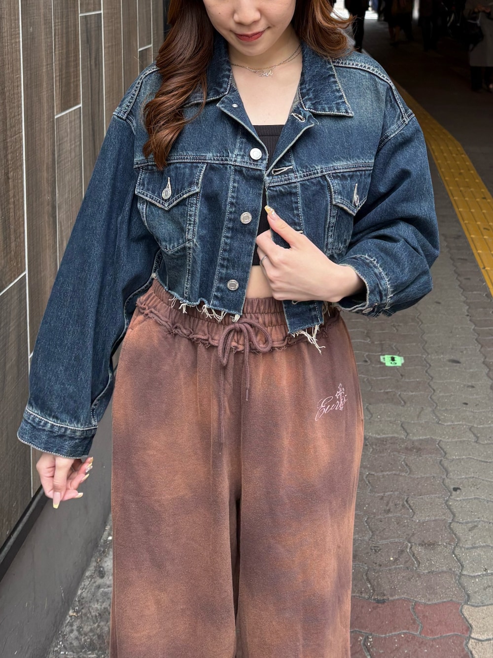 ブルー系のデニムジャケット、ブラウン系のスウェットパンツ、ブラック系のブーツを着用したレディースの春コーディネートの4枚目の写真