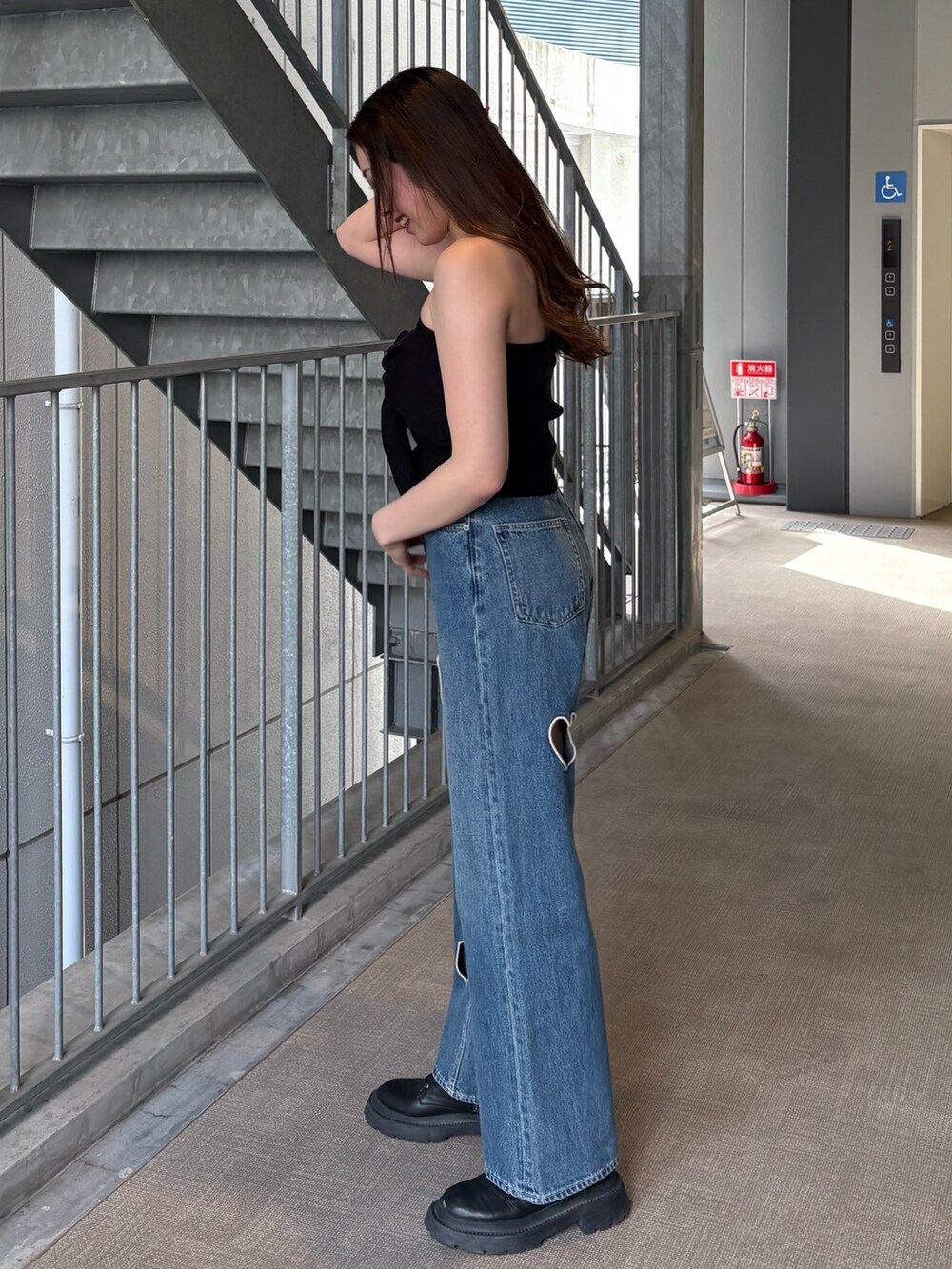 ブルー系のデニムパンツ、ブラック系のキャミソール、ブラック系のブーツを着用したレディースの春コーディネートの2枚目の写真