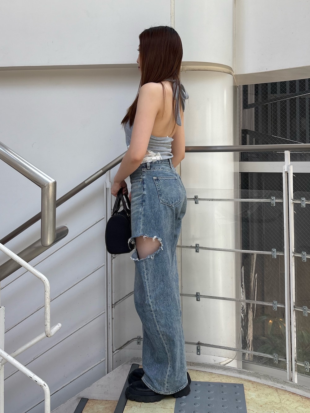 ブルー系のデニムパンツ、ブラック系のボストンバッグ、ブラック系のブーツを着用したレディースの夏コーディネートの2枚目の写真