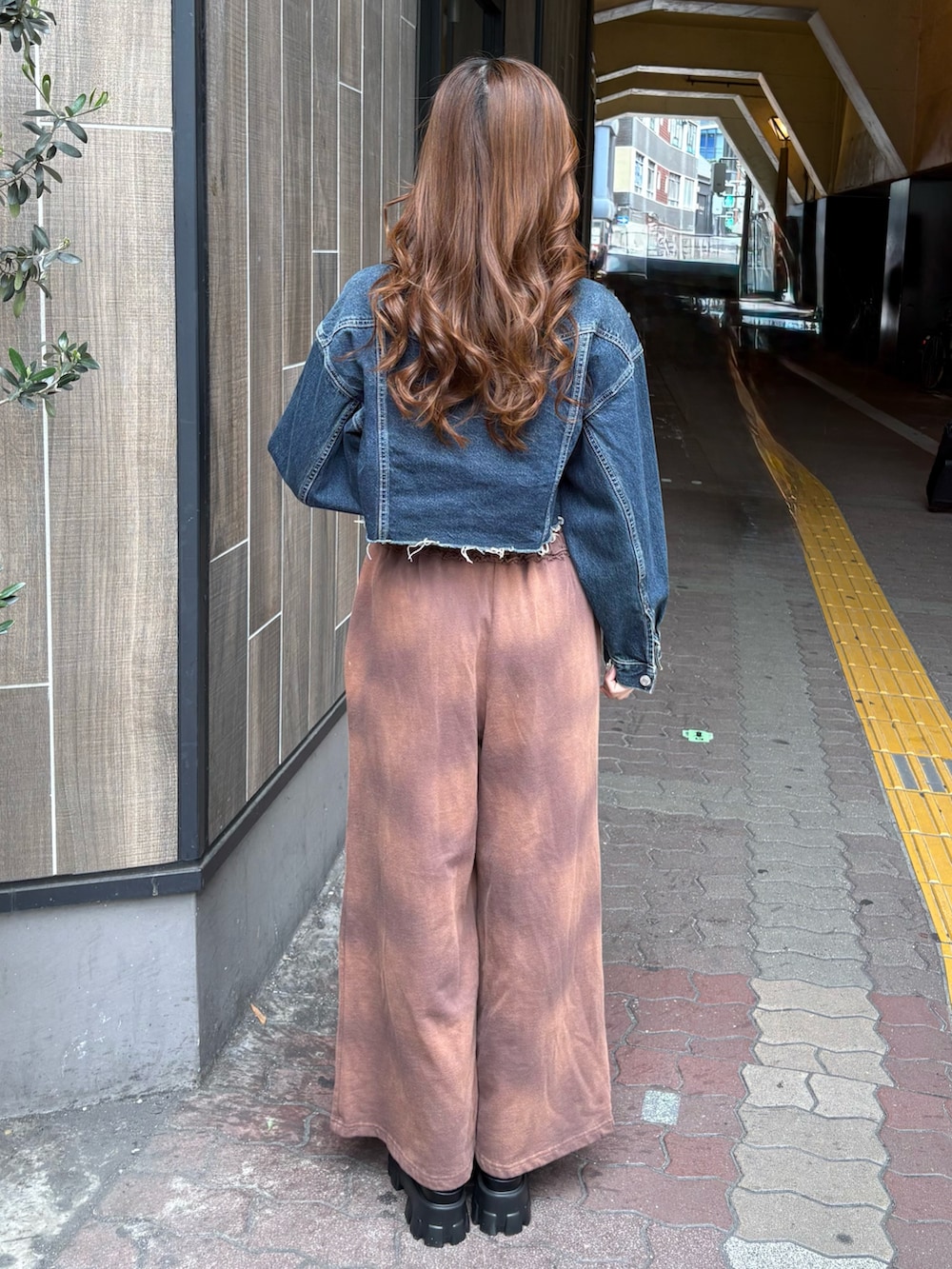 ブルー系のデニムジャケット、ブラウン系のスウェットパンツ、ブラック系のブーツを着用したレディースの春コーディネートの3枚目の写真