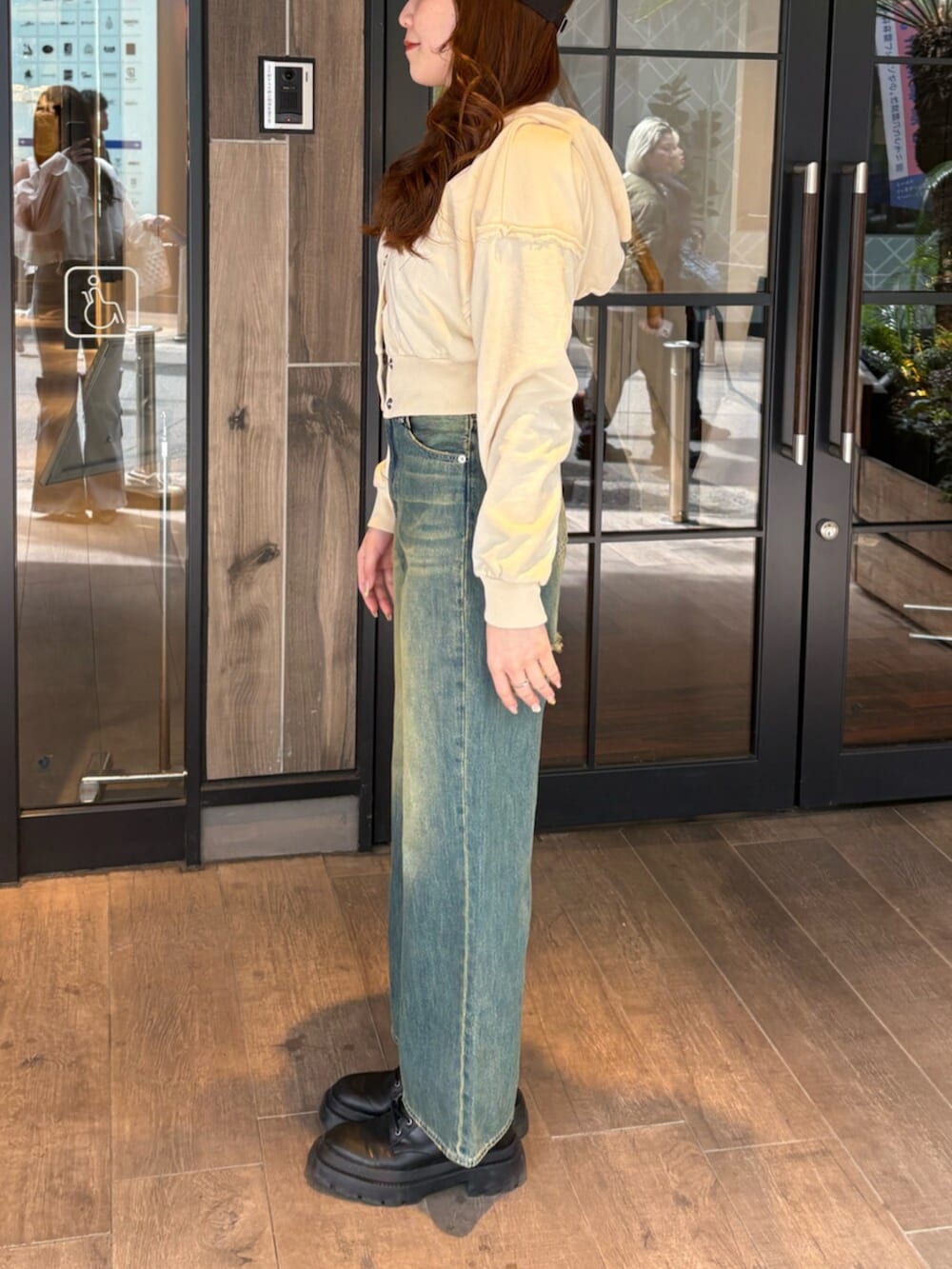 ブラック系のブーツ、ブルー系のデニムパンツ、ホワイト系のパーカーを着用したレディースの春コーディネートの2枚目の写真