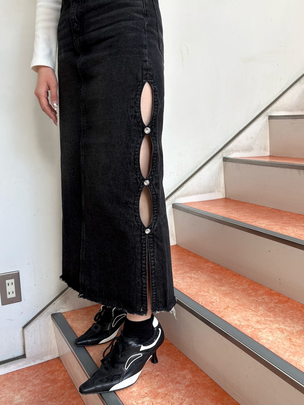 ホワイト系のTシャツ/カットソー、ブラック系のデニムスカート、ブラック系のパンプスを着用したレディースの春コーディネートの6枚目の写真