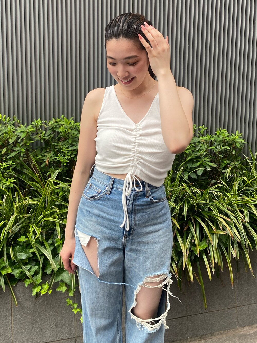 ホワイト系のタンクトップ、ブルー系のデニムパンツ、ブラック系のサンダルを着用したレディースの夏コーディネートの4枚目の写真