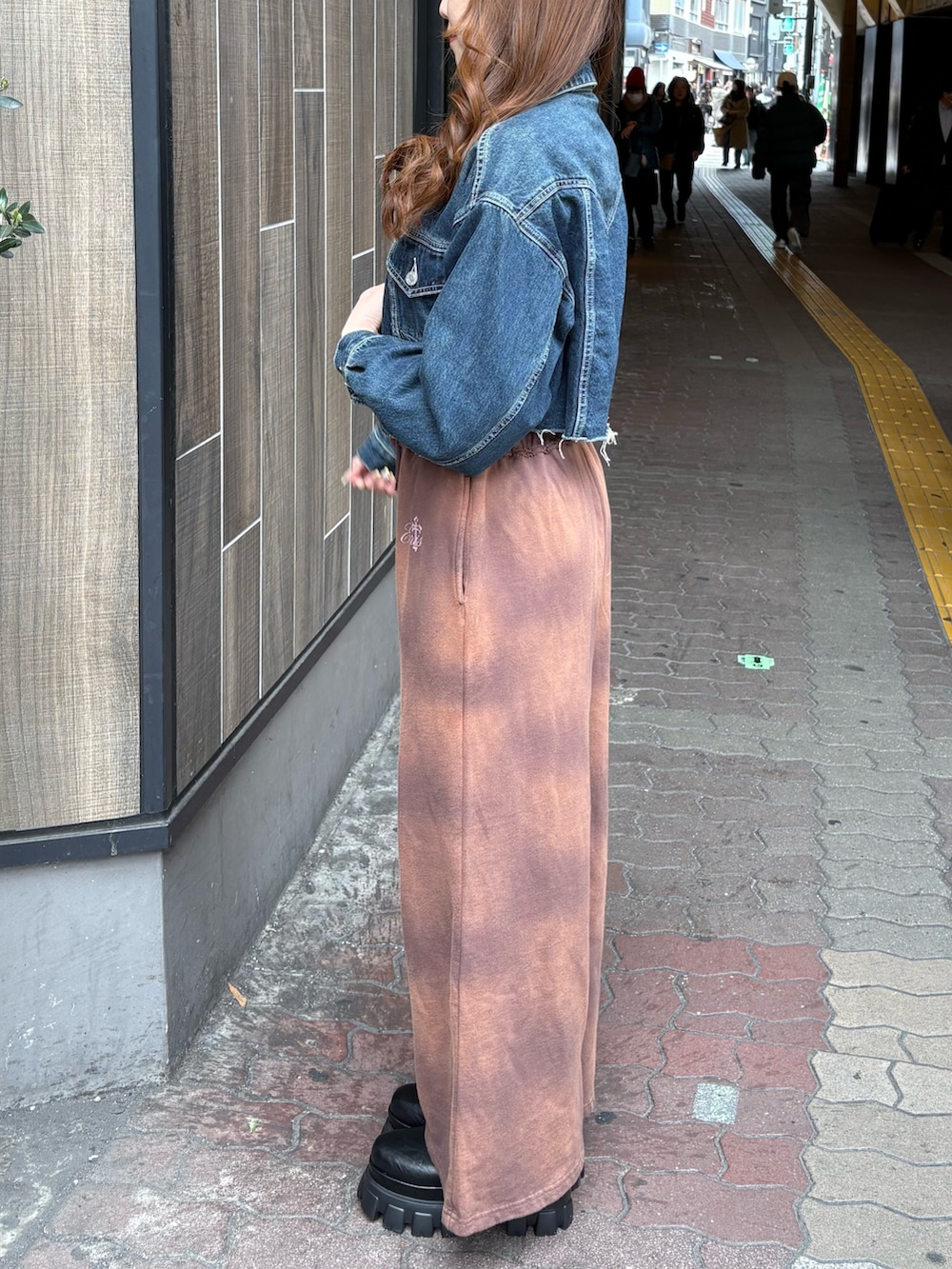 ブルー系のデニムジャケット、ブラウン系のスウェットパンツ、ブラック系のブーツを着用したレディースの春コーディネートの2枚目の写真