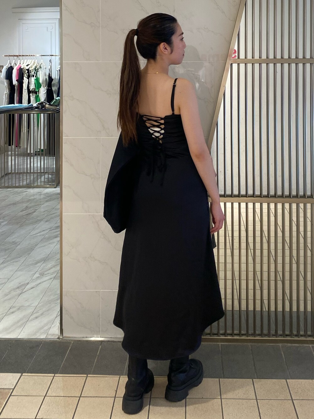 ブラック系のワンピース、ブラック系のトートバッグ、ブラック系のブーツを着用したレディースの夏コーディネートの2枚目の写真