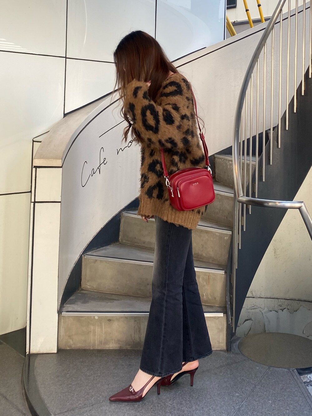 ブラック系のデニムパンツ、ブラウン系のニット/セーター、レッド系のショルダーバッグを着用したレディースの秋コーディネートの2枚目の写真