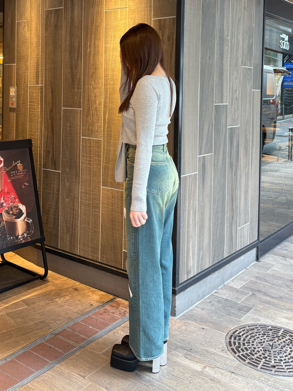 グレー系のニット/セーター、ブルー系のデニムパンツ、ブラック系のブーツを着用したレディースの冬コーディネートの2枚目の写真