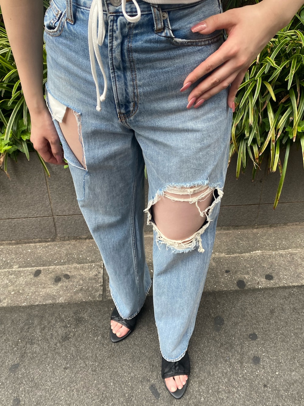 ホワイト系のタンクトップ、ブルー系のデニムパンツ、ブラック系のサンダルを着用したレディースの夏コーディネートの6枚目の写真