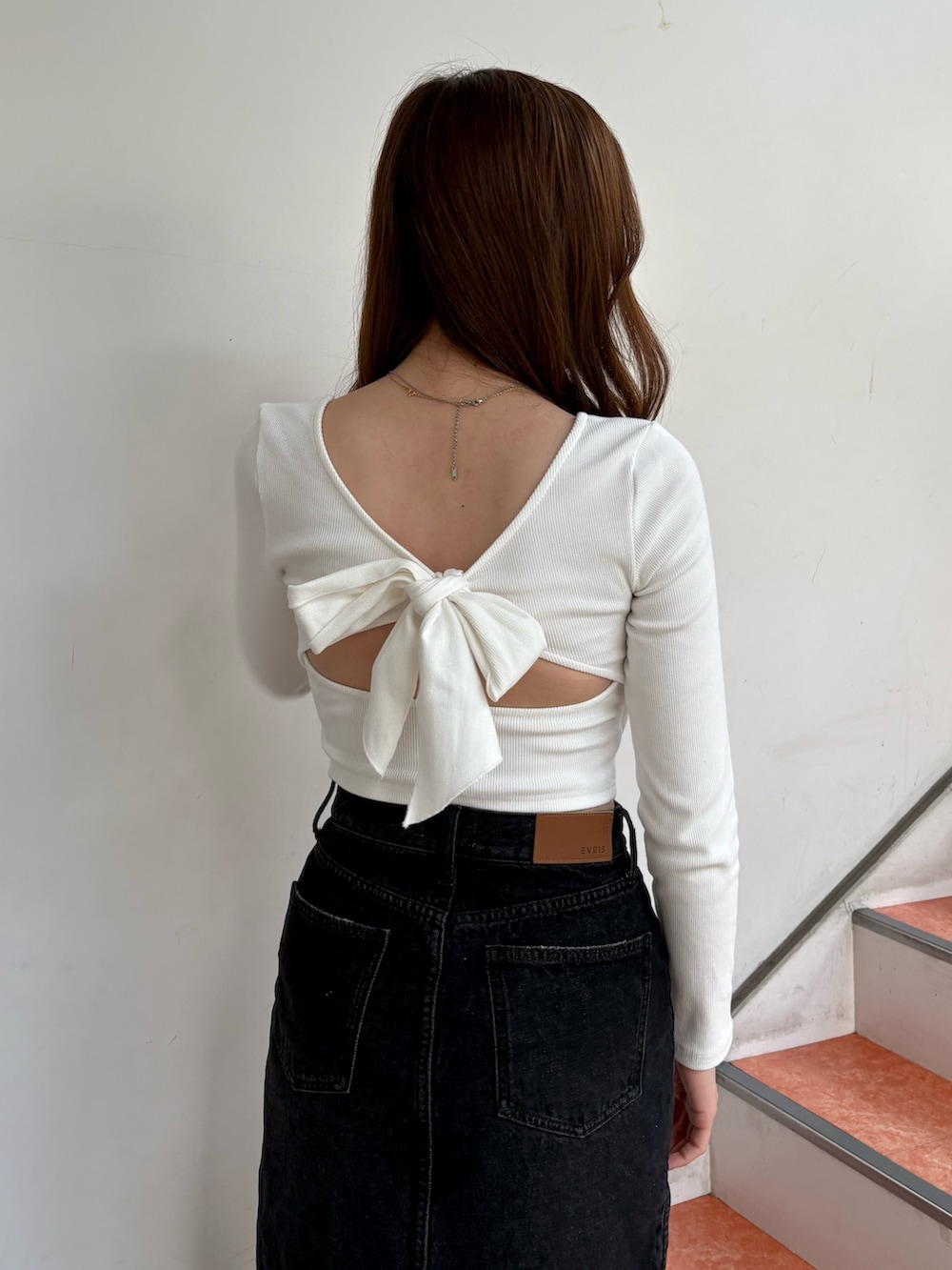 ホワイト系のTシャツ/カットソー、ブラック系のデニムスカート、ブラック系のパンプスを着用したレディースの春コーディネートの5枚目の写真