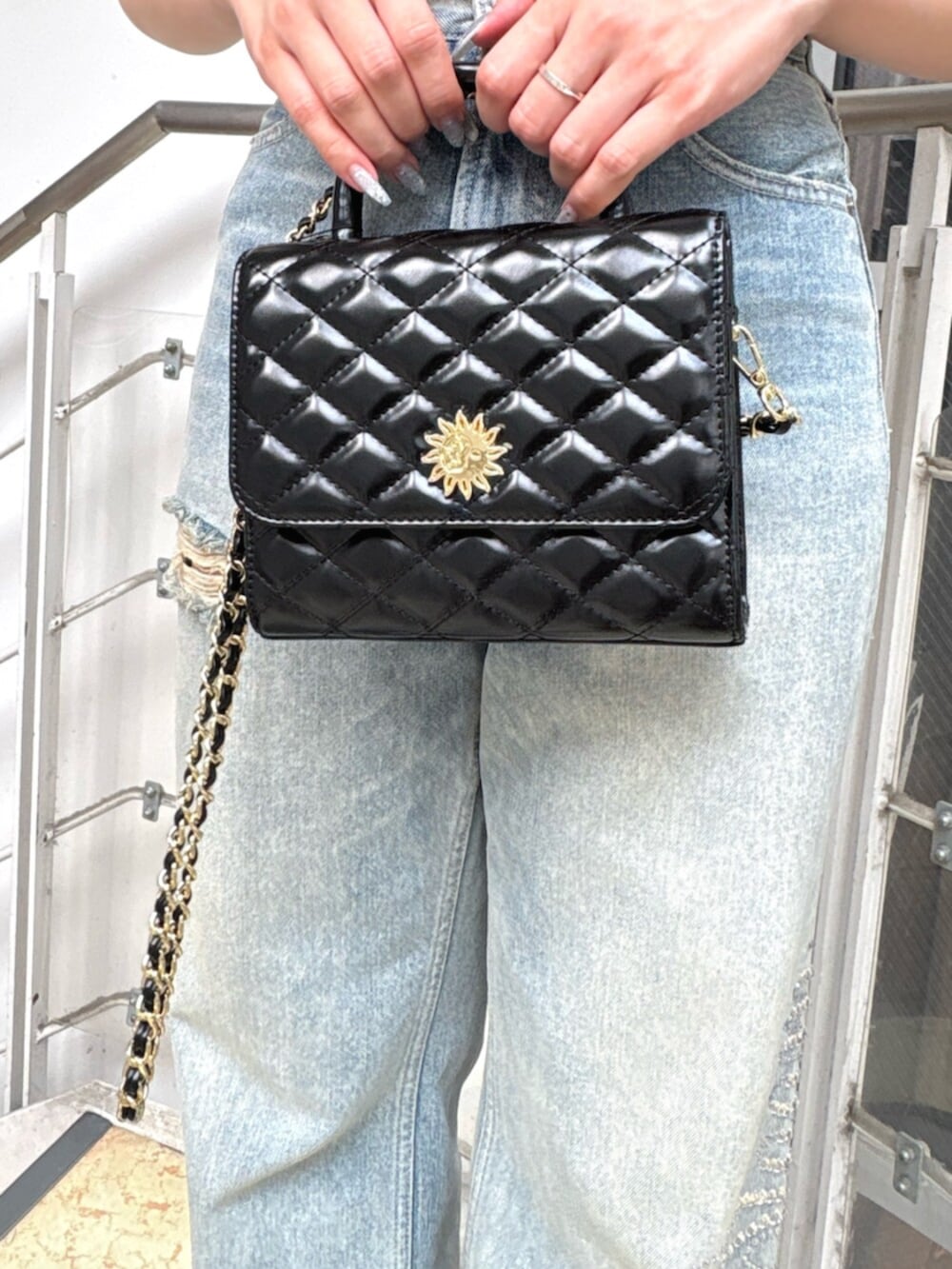 ブラック系のサンダル、ホワイト系のショルダーバッグ、ブルー系のデニムパンツを着用したレディースの夏コーディネートの4枚目の写真