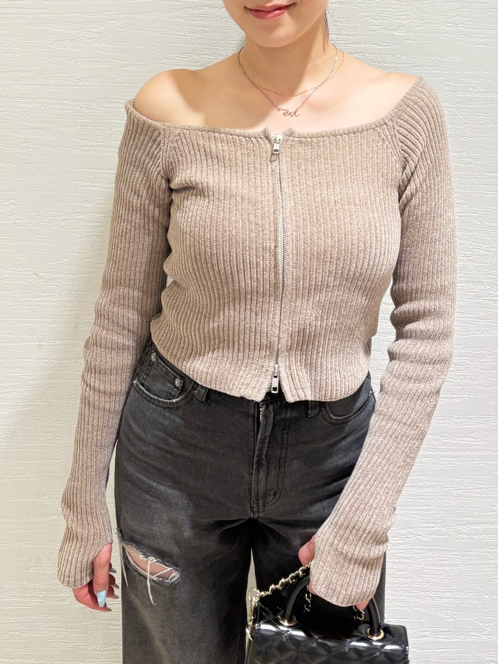 ブラック系のショルダーバッグ、ブラック系のデニムパンツ、ブラック系のブーツを着用したレディースの秋コーディネートの4枚目の写真