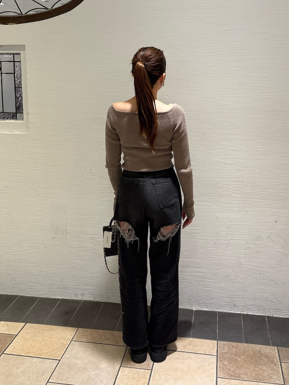 ブラック系のショルダーバッグ、ブラック系のデニムパンツ、ブラック系のブーツを着用したレディースの秋コーディネートの3枚目の写真