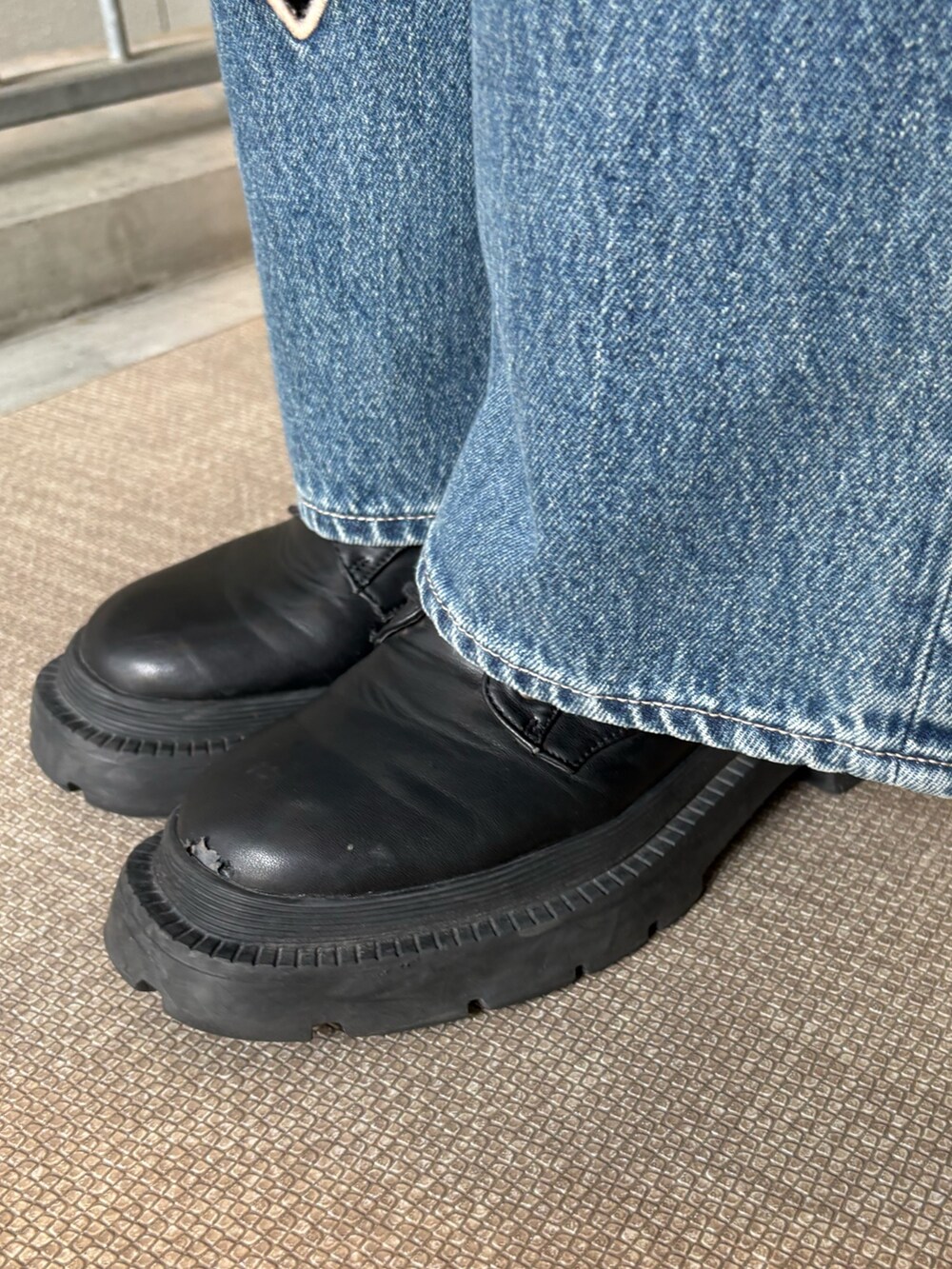 ブルー系のデニムパンツ、ブラック系のキャミソール、ブラック系のブーツを着用したレディースの春コーディネートの7枚目の写真