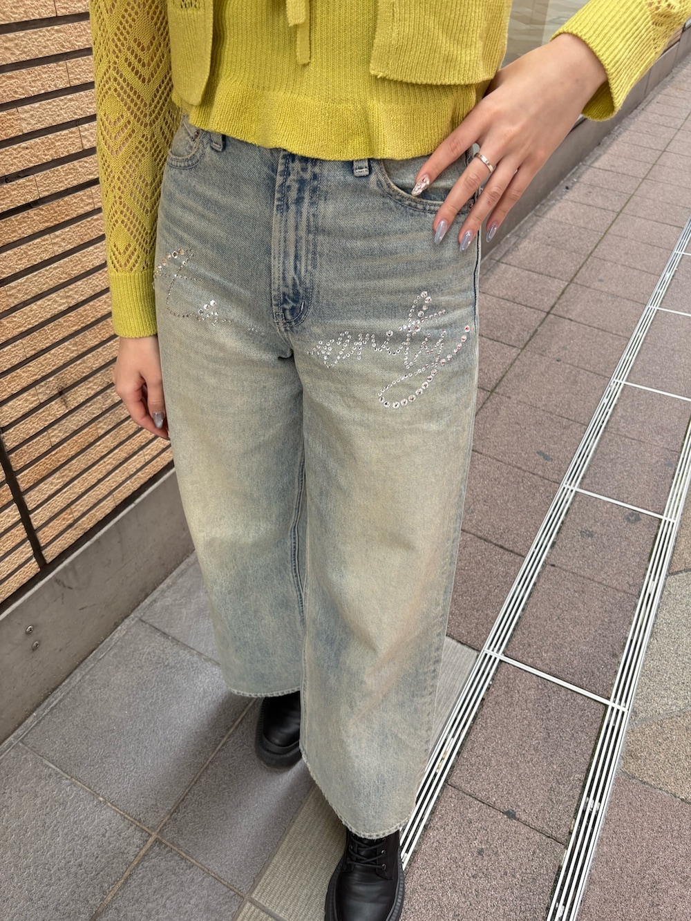 イエロー系のカーディガン/ボレロ、ブラック系のブーツ、ブルー系のデニムパンツを着用したレディースの春コーディネートの5枚目の写真