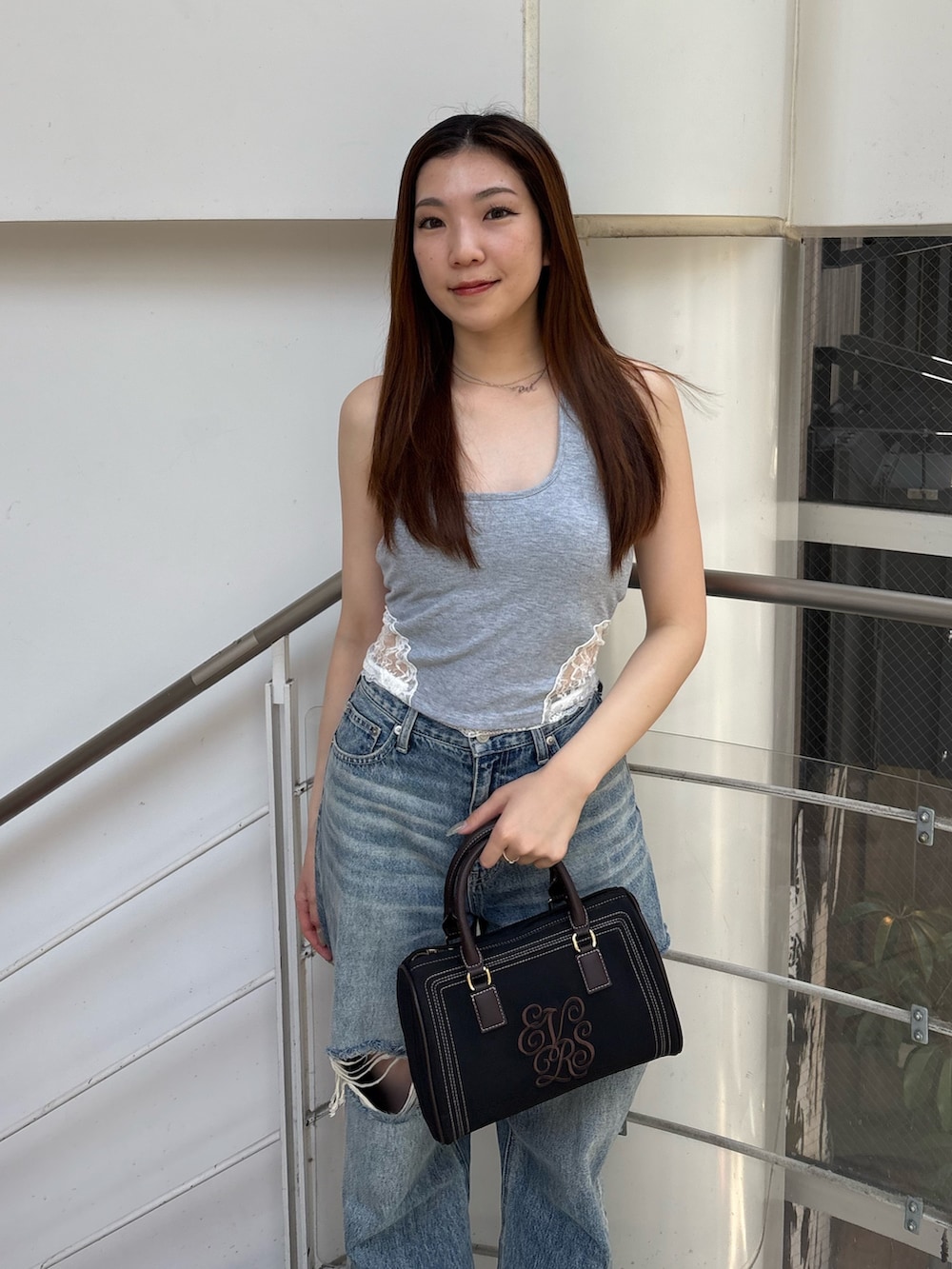 ブルー系のデニムパンツ、ブラック系のボストンバッグ、ブラック系のブーツを着用したレディースの夏コーディネートの4枚目の写真