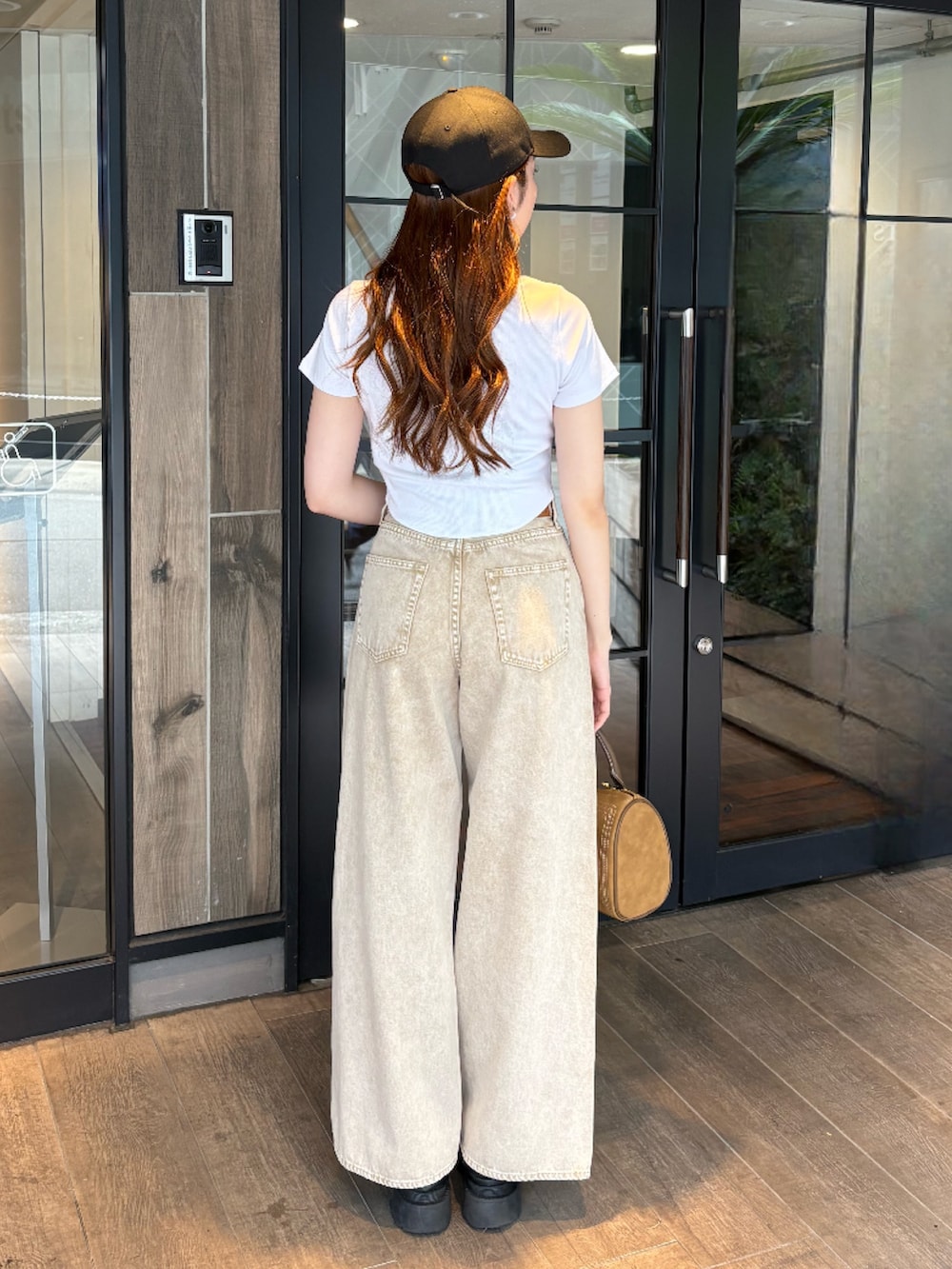 ブラウン系のボストンバッグ、ベージュ系のデニムパンツ、ブラック系のブーツを着用したレディースの夏コーディネートの3枚目の写真