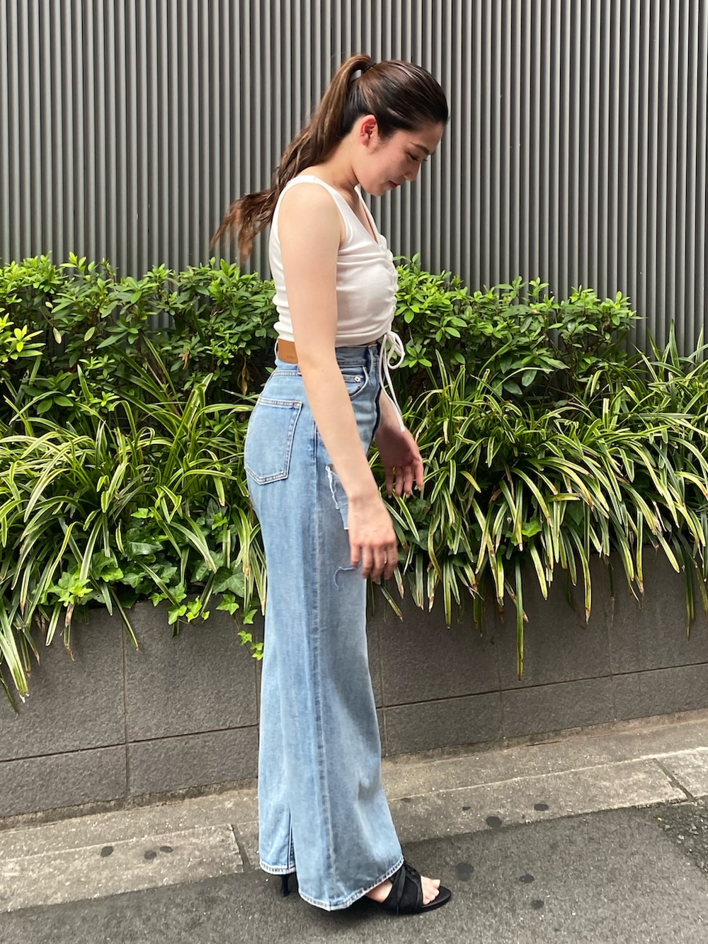 ホワイト系のタンクトップ、ブルー系のデニムパンツ、ブラック系のサンダルを着用したレディースの夏コーディネートの3枚目の写真