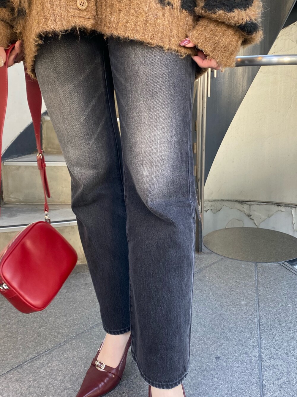 ブラック系のデニムパンツ、ブラウン系のニット/セーター、レッド系のショルダーバッグを着用したレディースの秋コーディネートの6枚目の写真